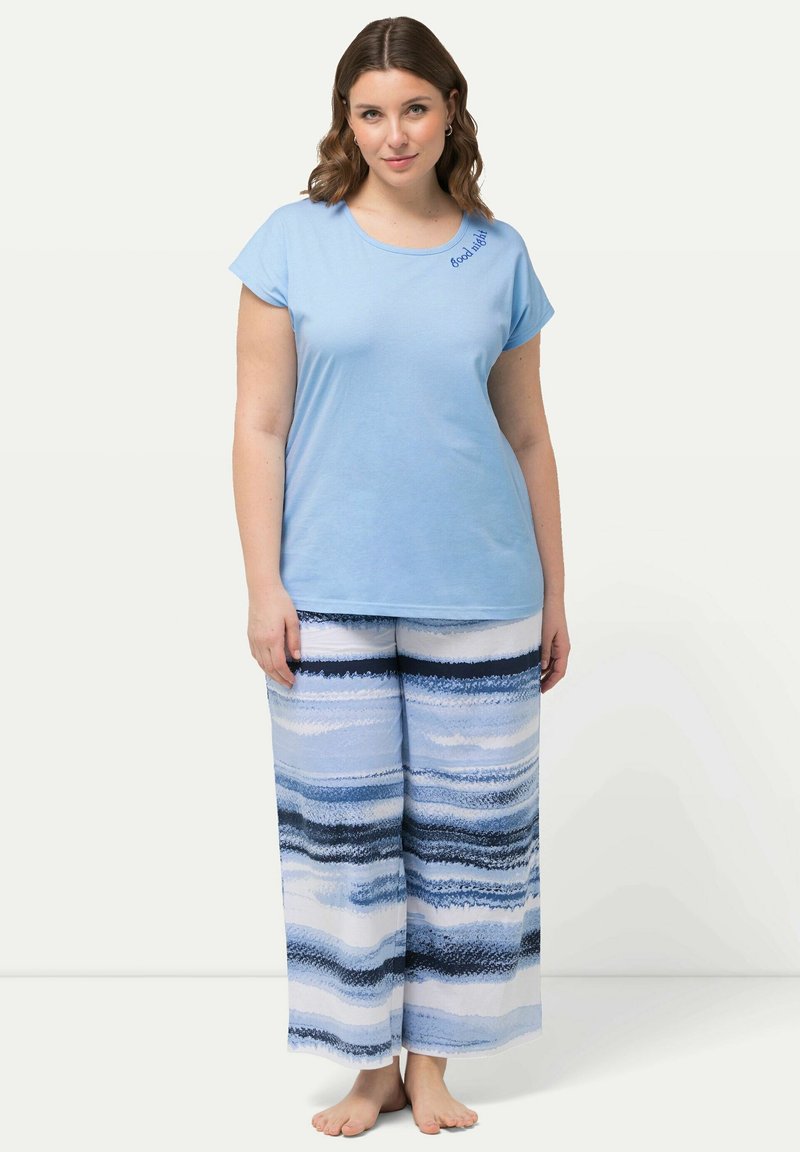 Ljusblå bomullströja med korta ärmar och broderad text "Good Vibes", tillsammans med vida byxor i blå och vita ränder.