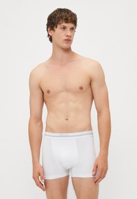 Boxeri din bumbac alb, cu un design ajustat, textură moale și un elastic de culoare gri deschis cu numele mărcii imprimat pe el.