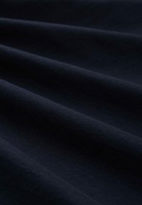 Tejido azul marino oscuro con una textura suave, mostrando suaves pliegues caídos y un color uniforme sin patrones visibles ni detalles de hardware.