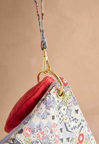 Prešívaná kabelka s kvetinovým a geometrickým vzorom, prevažne v pastelových farbách, s červeným vnútrom a zlatými kovovými detailmi.