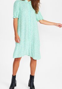 Jasnoniebieska sukienka w kwiatowy wzór, z krótkimi bufkami, kołnierzykiem i zwiewnym dołem. W połączeniu z czarnymi botkami za kostkę.