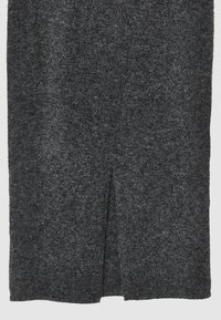 Pull gris foncé avec une finition texturée et duveteuse. Présente une fente en forme de V au centre de l'ourlet avant pour un détail supplémentaire. Matière douce et chaude.