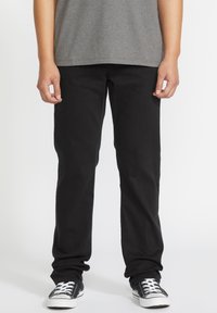 Black denim jeans with a straight leg fit, worn with a gray t-shirt, and black and white sneakers. Smooth texture, no visible patterns.