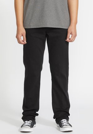Black denim jeans with a straight leg fit, worn with a gray t-shirt, and black and white sneakers. Smooth texture, no visible patterns.