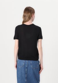 Svart kortärmad t-shirt med rund halsringning och avslappnad passform, tillsammans med en ljusblå denimkjol. Slät textur, minimal detaljer.
