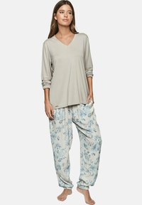 Haut gris clair à manches longues avec un col en V et des manches retroussées, associé à un pantalon beige à imprimé floral ample avec des poignets élastiques.