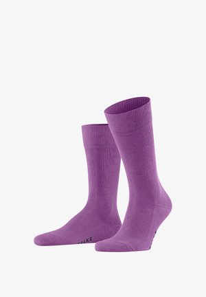 Chaussettes de crew violettes en matériau doux, avec un poignet côtelé et une texture lisse, arborant un logo le long de la semelle.