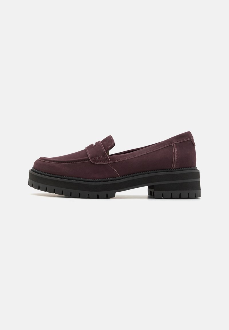 Mocassin en cuir violet foncé avec semelle épaisse à crampons noirs et petit talon bloc, coutures visibles et détail de sangle sur le dessus.