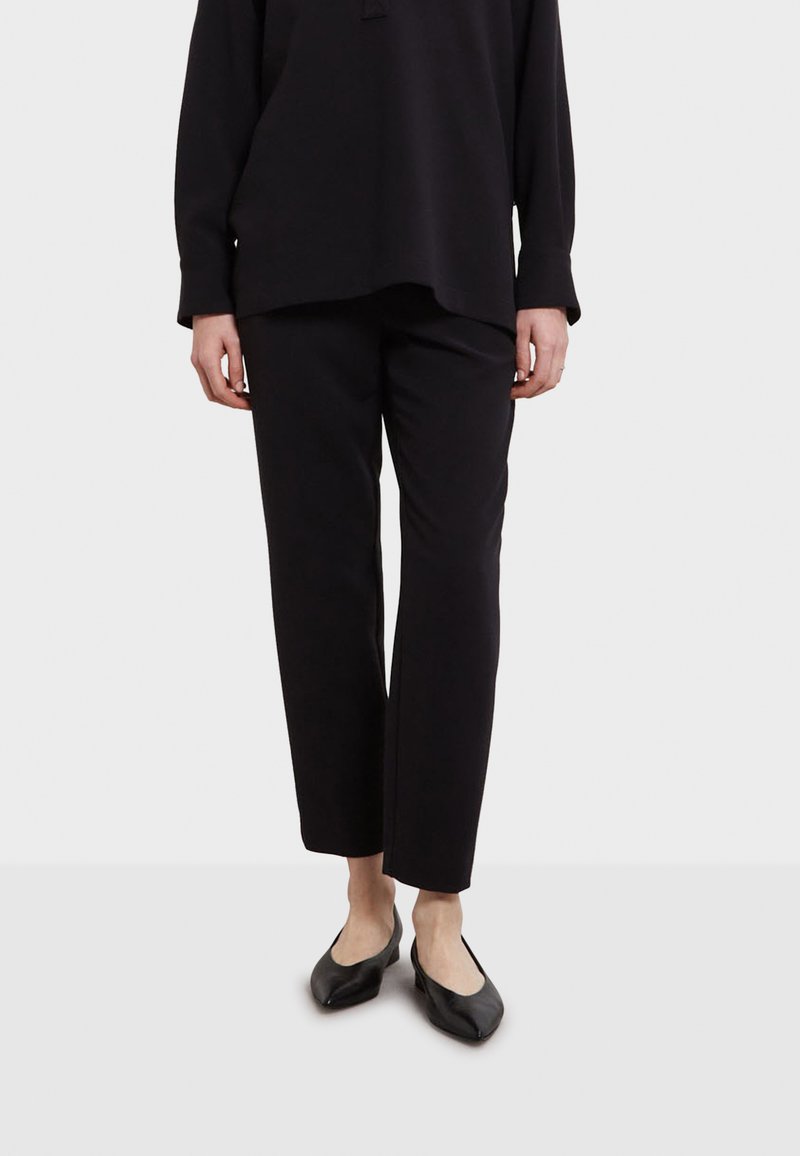 Zwarte, relaxte broek van zachte stof met een elastische tailleband; gladde textuur en recht gesneden pijpen.