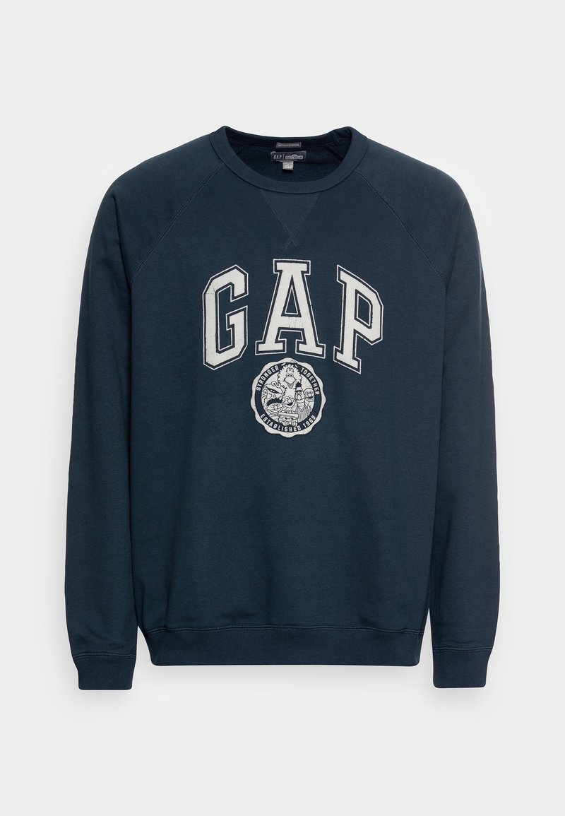 Sweat-shirt bleu marine avec col rond et manches raglan. Présente un grand logo "GAP" et un design graphique circulaire à l'avant.