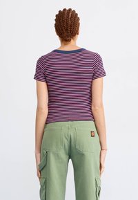 Top aderente a manica corta con strisce orizzontali blu navy e multicolore; abbinato a pantaloni cargo a vita alta verde oliva con tasche.