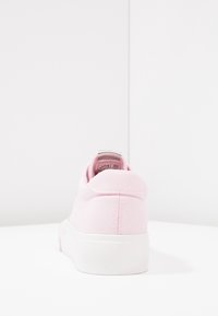 Różowy tenisówka z materiału płóciennego o niskim profilu, biała gumowa podeszwa i przeszycia na pięcie. Srebrny akcent na tylnej pętelce.