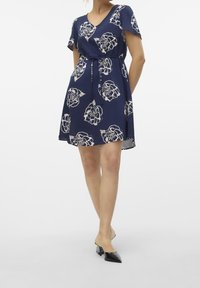 Mörkblå kort klänning med ett blommönster i kräm, med V-ringning, korta ärmar och midjeband för en figurnära silhuett.