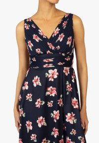 Blumenkleid aus weichem Stoff mit navyfarbenem Hintergrund und pinken sowie weißen Blumenmustern, einem figurbetonten Oberteil und einem ausgestellten Rock.