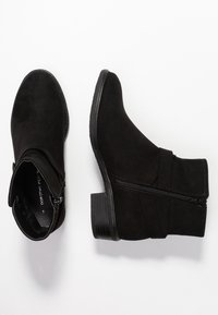 Botines de ante negro con tacón bajo, que cuentan con una cremallera lateral y un detalle fruncido en el tubo, textura suave y punta redondeada.