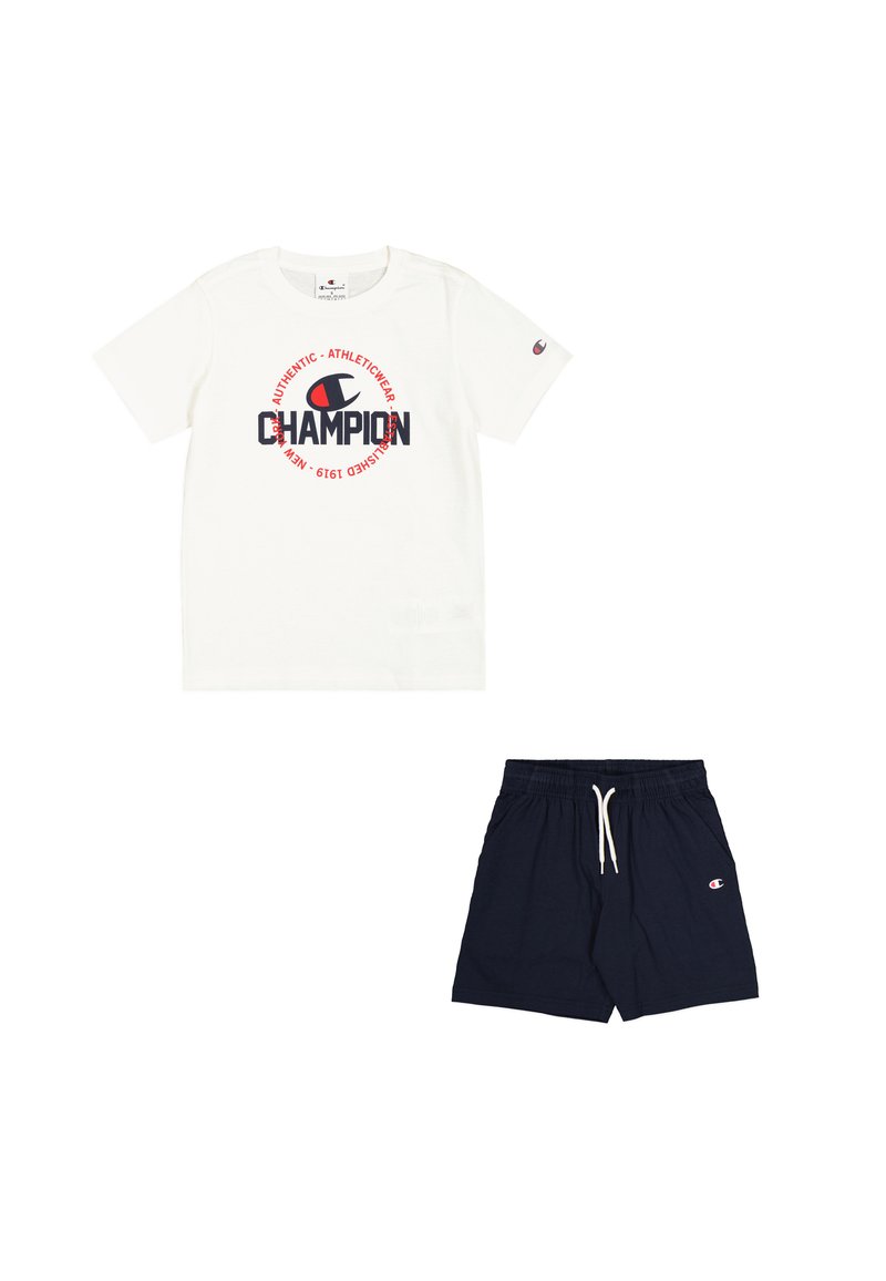 T-shirt bianca a maniche corte con logo "Champion" rosso e blu navy; abbinata a pantaloni corti blu navy con vita elastica e accento con logo.