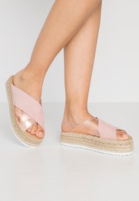 Růžové espadrilové sandály s křížovými popruhy a kovovým akcentem, s jutovou podrážkou, které mají design na klínu a texturovanou bílou gumovou podrážku.