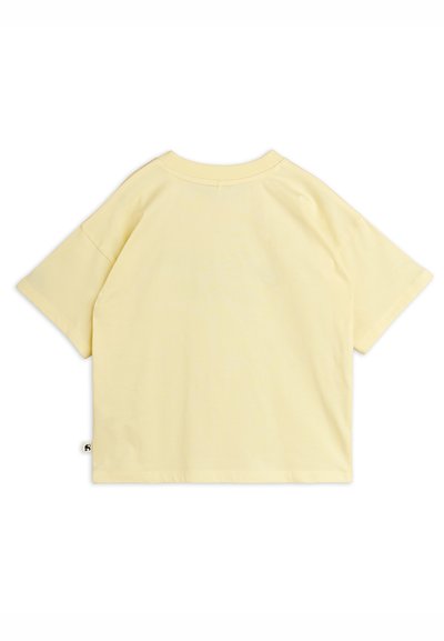 Ανοιχτό κίτρινο βαμβακερό T-shirt με κοντά μανίκια, απλωμένο επίπεδα, δείχνοντας την πίσω πλευρά με στρογγυλή λαιμόκοψη και μικρή ετικέτα στην πλευρική ραφή.