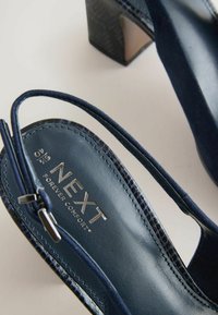 Námořnické modré slingback podpatky z nubuku s texturovaným koženým akcentem, s prostředním podpatkem a stříbrným logem na stélce.