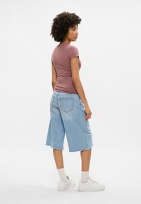 Heled m kunde T-särk, kõrge vöökoht, laiad helesinised denimpüksid, rebitud serv, koos valgete tossude ja pahkluu sokkidega.