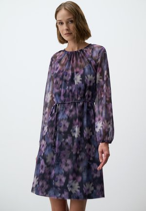 Bloemenprint jurk van doorschijnende stof, met tinten paars en blauw. Lange mouwen, ronde halslijn en een stoffen riem in de taille.