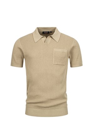 Kortermet beigefarget piké med ribbestruktur, flat krage og en enkelt brystlomme. Har rett nederkant og en tettsittende design.