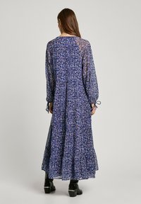 Pitkä, sininen kukkakuosiset mekko, jossa on pitkät hihat, kerroksellinen muotoilu ja pehmeä kangas. Mekossa on pyöreä pääntie ja säädettävät nauhakiinnitykset hihoissa.