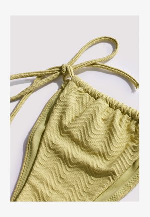 Parte inferior de bikini verde claro con textura y lazos ajustables en los laterales, exhibida sobre un fondo blanco liso.