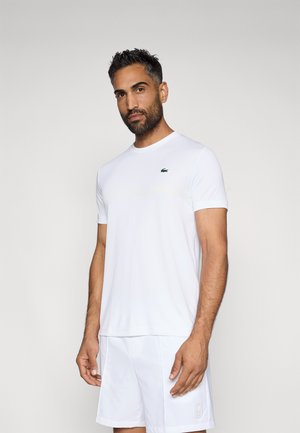 Weißes Sport-T-Shirt mit Rundhalsausschnitt und kurzen Ärmeln, ausgestattet mit subtilen gelben Streifen und einem grünen gestickten Logo auf der Brust.