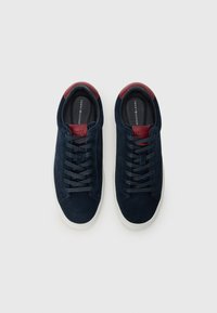 Mørkeblå suede sneakers med en strukturert finish, med burgunderdetaljer på hælen og en hvit gummisåle; snøring.