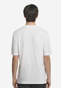 Hvid kortærmet t-shirt med rund hals, lavet af letvægtsstof. Har et ensfarvet design bagpå uden synlige logoer eller mønstre.