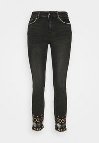 Jeans skinny negros con botón y cremallera, que presentan coloridos bordados de patrones florales alrededor de los puños de los tobillos.