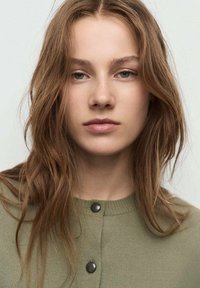 Cardigan verde con scollo rotondo, chiusura a bottoni e tessuto texturizzato. Il modello ha capelli mossi, trucco neutro e un'espressione priva di emozioni.