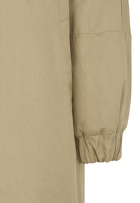 Beige, textured fabric close-up featuring a voluminous, gathered sleeve and clean seam lines for a modern silhouette.