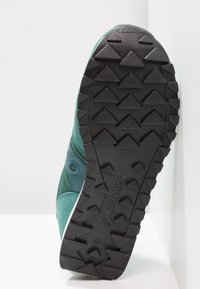 Baskets turquoise avec une semelle extérieure en caoutchouc noir texturé dotée de crampons triangulaires pour une meilleure adhérence. Tige en suède et en matériau synthétique.