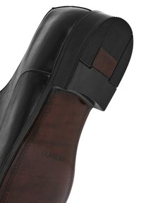Chaussure en cuir noir avec un dessus lisse, un bout légèrement arrondi et une semelle en caoutchouc texturé. Présente une semelle intérieure en cuir marron avec un logo en relief.