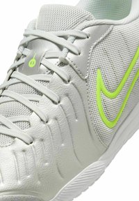 Gray athletic shoe with a textured finish, mesh panels, and neon green accents. Features laces and molded detail along the midsole.