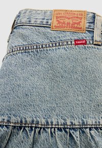 Τζιν φούστα με ανοιχτό μπλε ξέβγαλμα, με βολάν στο τελείωμα, πορτοκαλί ραφές και δερμάτινη ετικέτα που γράφει "Levi Strauss & Co."