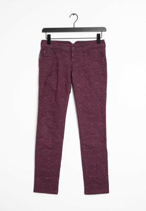 Bordeaux denim broek met een gemarmerd bloemenpatroon, met vijf zakken en een knoopsluiting, hangend aan een zwarte haak.