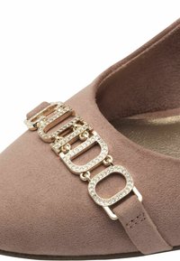 Scarpa in suede rosa con un accento in hardware dorato e strass attaccati sulla parte frontale. Texture liscia con un design a punta tonda.