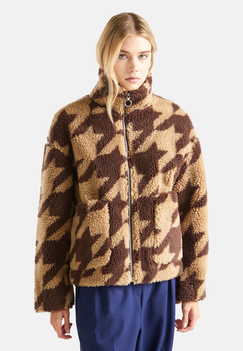 Braun und beige Houndstooth-Muster Kunstpelzjacke mit hohem Kragen, vorderem Reißverschluss und zwei seitlichen Taschen. Weiches, strukturiertes Material.