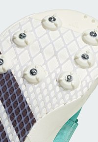 Suola della scarpa in gomma bianca, con borchie metalliche circolari, un motivo di presa testurizzata e accenti color acquamarina lungo i bordi.