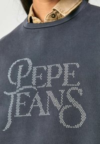Felpa grigia scura con il testo "Pepe Jeans" decorato con strass argentati. Collo a coste e tessuto texturizzato.