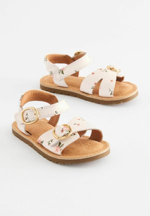 Witte bloemen sandalen met twee verstelbare banden, een gouden gesp en een zachte bruine gevoerde voetbed met een gestructureerde zool.