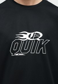Tricou negru texturat cu text alb stilizat "QUIK" și un grafic cu un baschet în flăcări deasupra literelor în zona pieptului.