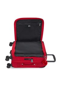 Valise rouge à quatre roues ouverte, montrant un intérieur noir vide avec une poche en filet zippée et une poignée extensible avec un porte-clés rouge attaché.