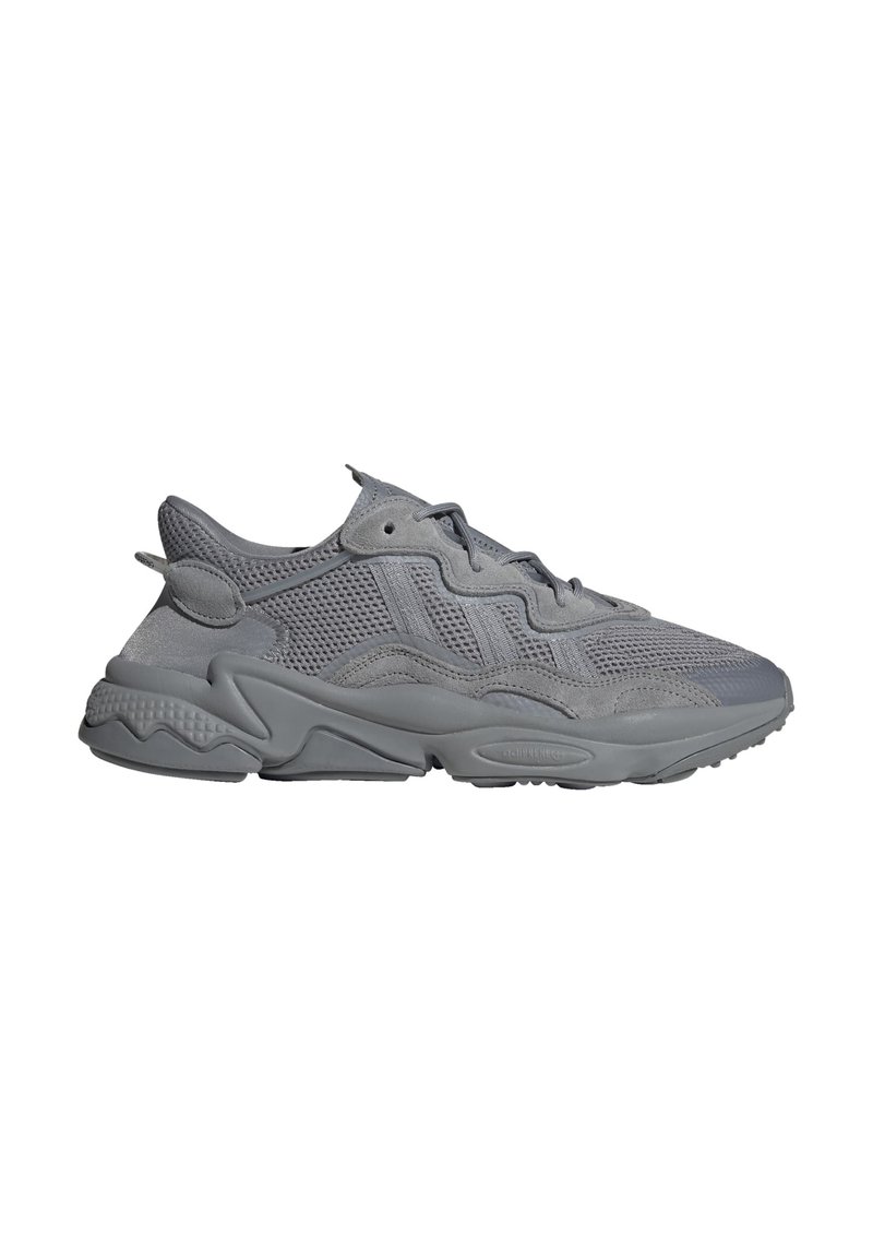 Scarpe da ginnastica grigie realizzate con materiali in rete e suede. Presentano una suola testurizzata, un design con lacci e una forma ergonomica. Vista laterale mostrata.