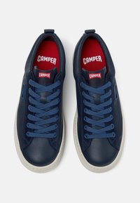 Mörkblå lädersneakers med rund tå, kontrasterande röda innersulor och blå skosnören. Har en diskret logotyp och vit gummisula.