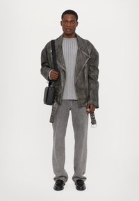 Overdimensjonert grå lærjakke med sølvfarge detaljer, stripete grå genser, grå denimbukser og svart messenger-veske. Svarte sko fullfører antrekket.
