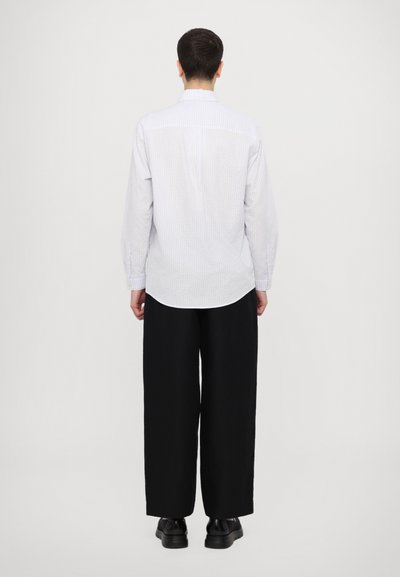 Camisa de manga larga a rayas azul claro y blanca con cuello abotonado, dobladillo redondeado y puños, combinada con pantalones anchos negros y zapatos negros.